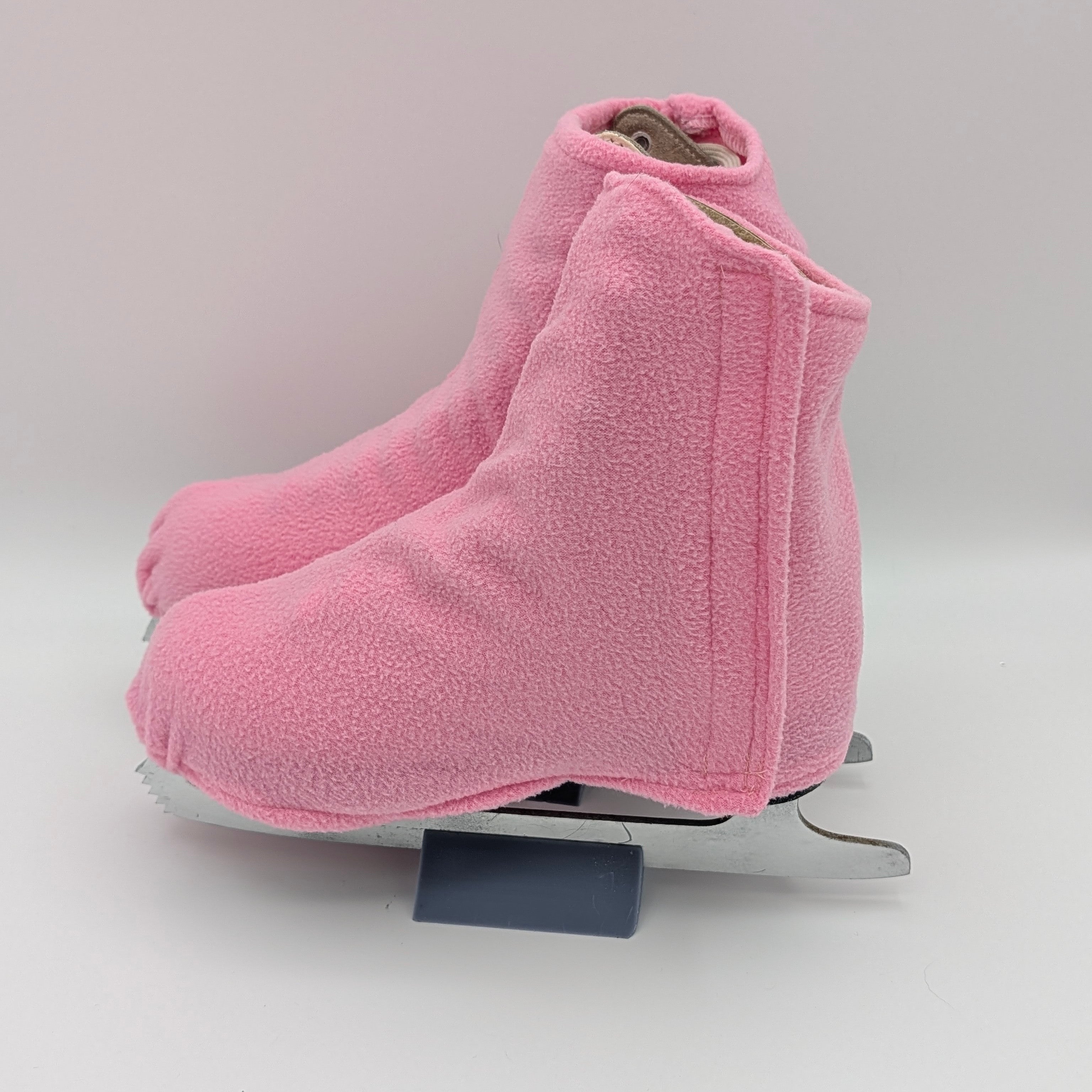 Pink fleece figure skate boot covers on a white background