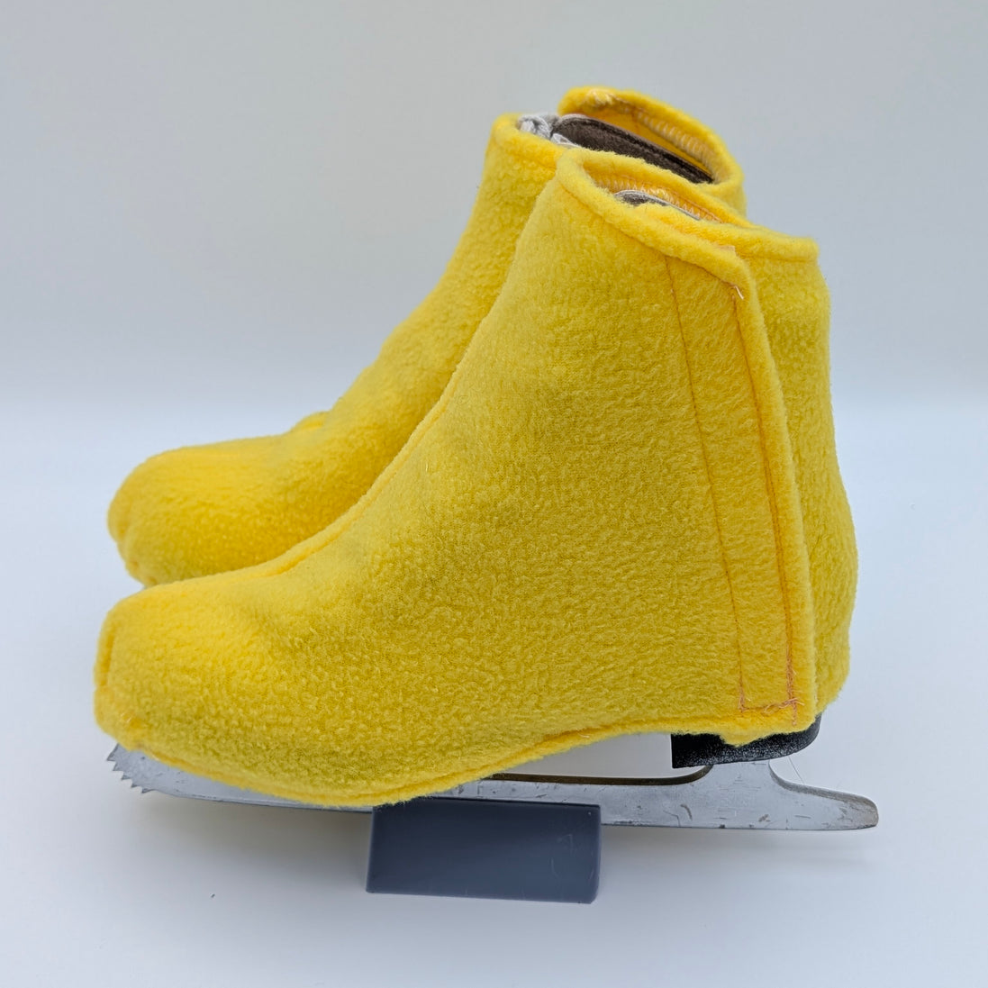Bright yellow figure skate boot covers on a white background